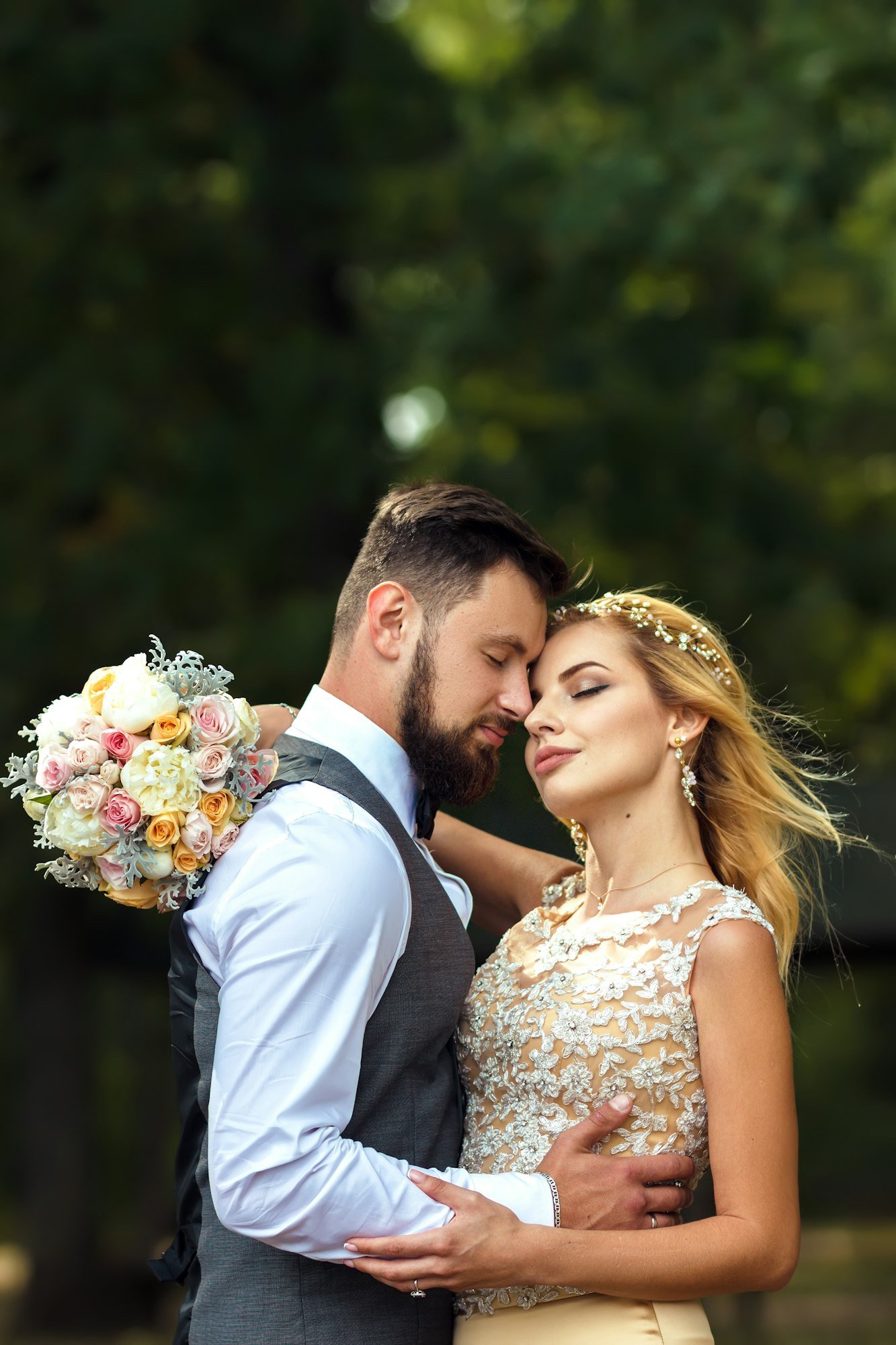 Stylish couple of happy newlyweds posing in the park on their wedding day. Perfect couple bride.